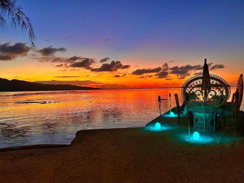 a bench on the shore of a lake at sunset at EDEN Private Island TAHAA in Patio