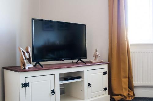 a flat screen tv on a white entertainment center at The Brown Box Holiday Let in Loftus