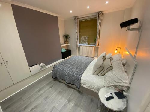 a bedroom with a bed and a table and a window at Central Private Double Bedroom in a 2bedroom Apartment, connected via underground, overground and many bus routes in London