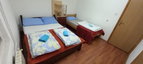 two beds in a small room with blue pillows on them at Vendela sobe in Banja Luka