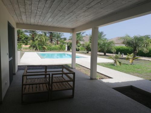 une terrasse couverte avec deux bancs et une piscine dans l'établissement Villa Rosso, à Cap Skirring
