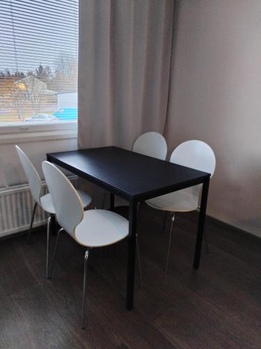 una mesa negra con sillas blancas y una ventana en Viihtyisä yksiö Korialla, en Kouvola