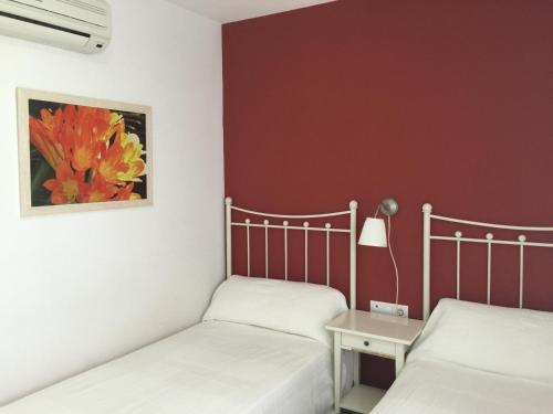 2 camas en una habitación con una pared roja en Hostal Monteluna, en Rociana