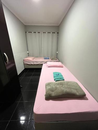 two beds in a room with pink and green sheets at Toca do Tatu in Itu
