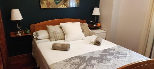 een slaapkamer met een bed met witte lakens en kussens bij Vigo, Céntrico Rosalía, parking incluido en festivos in Vigo