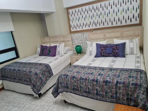 two beds sitting next to each other in a bedroom at Apartamento Riviera, lake Panajachel in San Jorge La Laguna