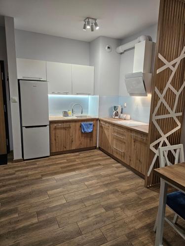 a kitchen with a white refrigerator and wooden cabinets at Apartament z wodą termalną in Uniejow