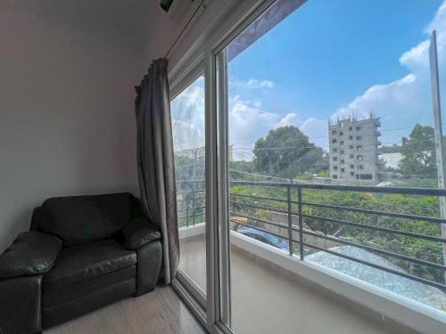 a living room with a couch and a large window at Hotel Elite by Agira- Spacious Apartments with Balcony in Yelahanka
