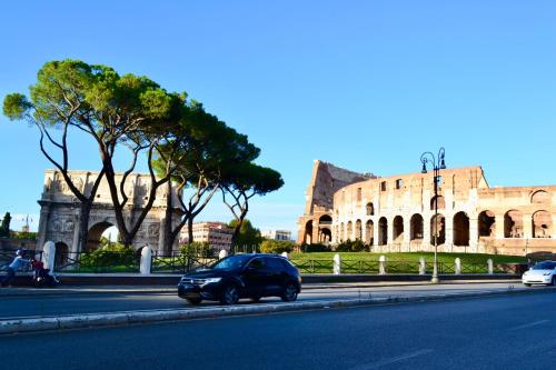 une voiture descendant dans une rue devant un bâtiment dans l'établissement ROMA LUXURY House Colosseo, à Rome