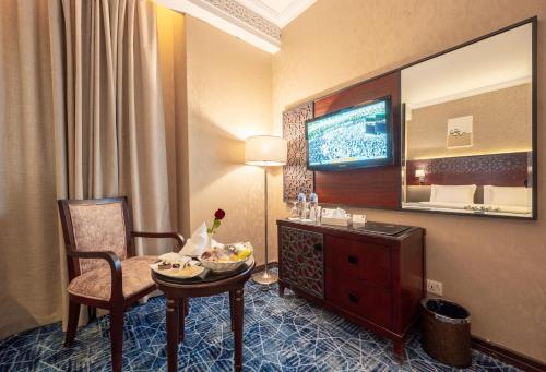 a hotel room with a table and a television at Shaza Regency Plaza Al Madinah in Al Madinah