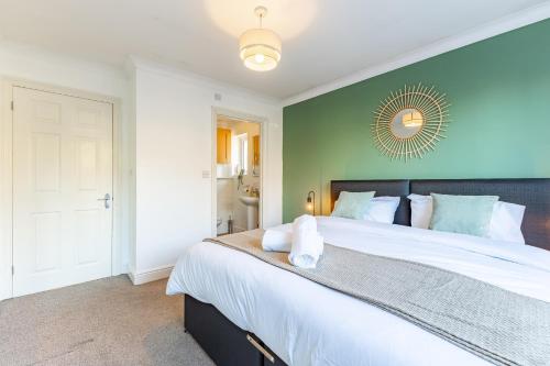 a bedroom with a large bed with a green wall at 5 Bed House Heathrow Egham Virginia Water Sleeps 7 or 8 sharing in Egham