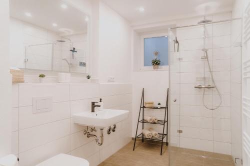 a white bathroom with a sink and a shower at Ferienwohnung am Weinberg in Bötzingen