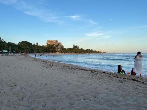 kobieta i dwójka dzieci na plaży w obiekcie Joli appartement avec vue sur la piscine w mieście Boca Chica