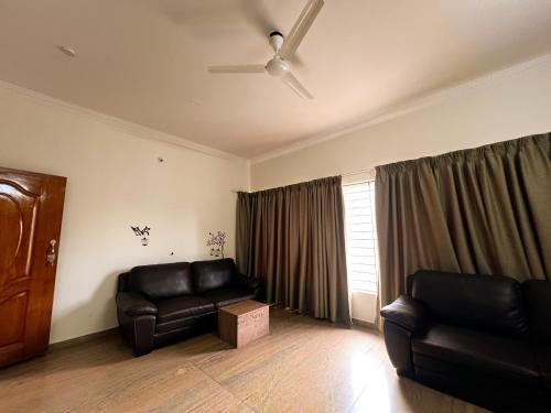 a living room with black leather furniture and a window at Hotel Elite By Agira Hotels-Free Airport Pickup or Drop in Yelahanka