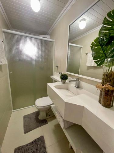 Un baño con lavabo, inodoro y espejo. en Apto 3 dorm completo - 100m Praia - Meia Praia, en Itapema