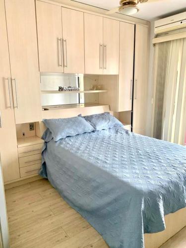 Un dormitorio con una cama con un edredón azul. en Apto 3 dorm completo - 100m Praia - Meia Praia, en Itapema