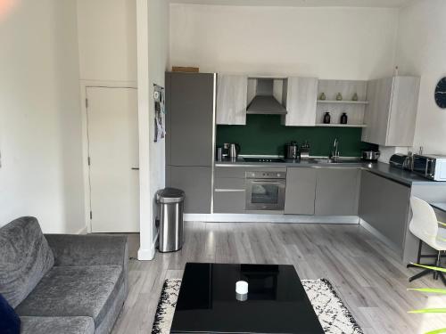 a living room with a couch and a kitchen at Spacious modern 1-bed apartment near Victoria Park & London Stadium in London