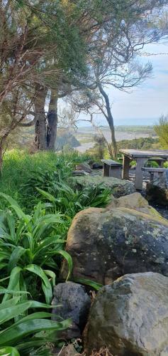 un parque con un banco y algunas rocas y árboles en Hapuku River Terrace a Eco Tiny House escape en Kaikoura