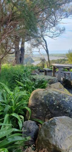 a park with a bench and some rocks and trees at Hapuku River Terrace a Eco Tiny House escape in Kaikoura
