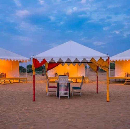 a table and chairs under a tent on the beach at Husain desert Safari Camp in Jaisalmer