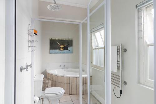 a white bathroom with a tub and a toilet at Corner House - Knysna in Knysna