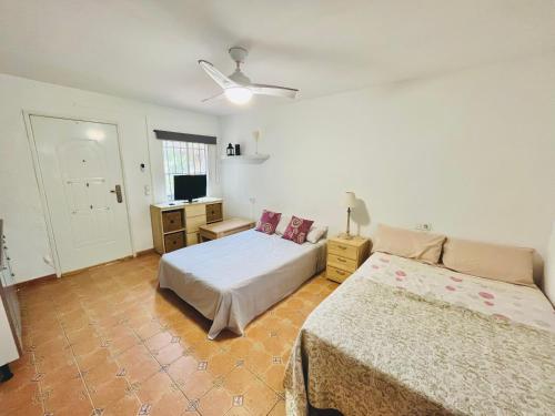 a bedroom with two beds and a flat screen tv at Estudio adosado con jardín y parking privado in Alicante