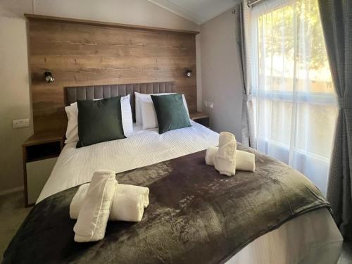 Silver Birch Lodge Aviemore في أفيمور: غرفة نوم بسريرين عليها مناشف