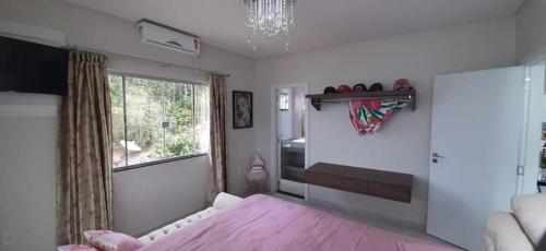 a bedroom with a pink bed and a window at casa nas marinas boa vista in Boa Vista Parecida