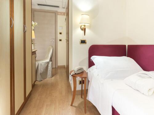 a hotel room with a bed and a table with a phone at Hotel Bikini in Rimini