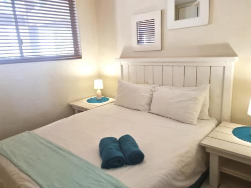 a white bed with two blue pillows on it at Santorini 105A in Margate