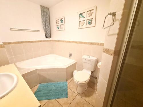 a bathroom with a toilet and a tub and a sink at Santorini 105A in Margate