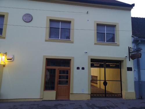 a white building with two doors and a fence at Fruškogorski biser in Sremski Karlovci