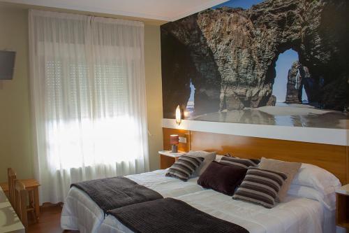 a bedroom with a bed with a painting on the wall at Hotel Bello in O Pino 