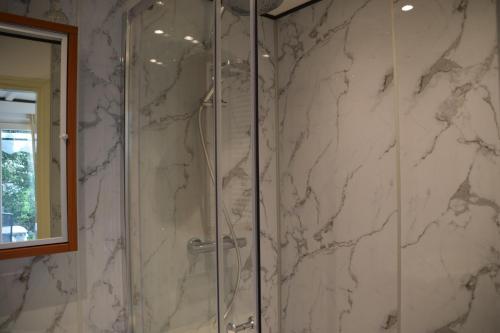 a bathroom with a shower with white marble walls at Anno 1877 appartement met tuin in Slenaken