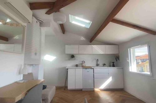 une cuisine avec des armoires blanches et une fenêtre dans l'établissement Heart of Nice-Rooftop Seaside Studio, à Nice