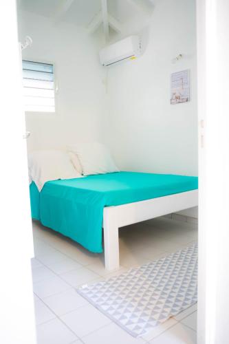 Camera bianca con letto e coperta blu di Domaine de la rosa spa privatif a Les Abymes