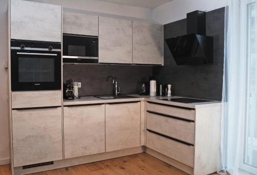 a kitchen with white cabinets and black appliances at Bella's Appartment - Beautiful, modern and next to metro in Vienna