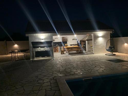 a house with a fireplace and a swimming pool at night at IDILA in Sveti Filip i Jakov