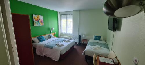 a bedroom with two beds and a green wall at Le 120 - Groupe Logis Hotels - Ex Auberge la Terrasse in La Châtaigneraie