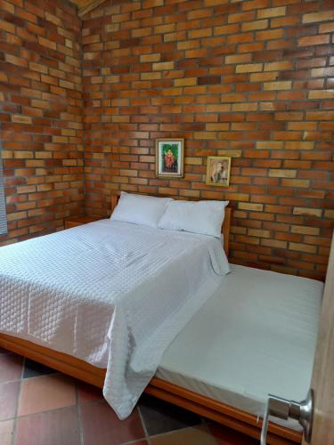 Cama en habitación con pared de ladrillo en Cabañas GARUTO, en Los Santos