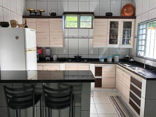 a kitchen with a white refrigerator and a black counter top at Casa Moreira in Pirenópolis