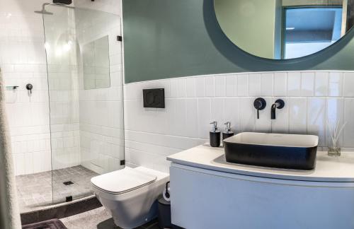 a bathroom with a sink and a toilet and a mirror at 208, The Duke - Luxury apartment with city views in Cape Town