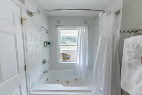 een witte badkamer met een douche en een raam bij Inn by the River in The Forks