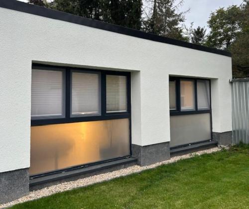 ein weißes Haus mit vier Fenstern an der Seite in der Unterkunft ruhig wohnen im kleinen Bungalow im Süden von Berlin in Teltow