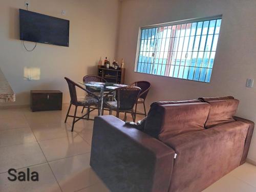 ein Wohnzimmer mit einem Sofa und einem Tisch mit Stühlen in der Unterkunft CASA DE TEMPORADA DE FÉRIAS in Santa Cruz Cabrália