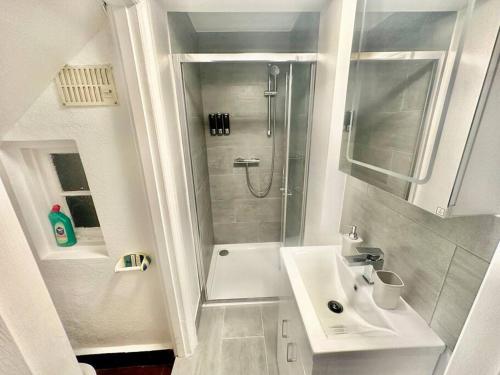 baño blanco con ducha y lavamanos en 4 Bed house in Daneby Road,SE6, en Catford