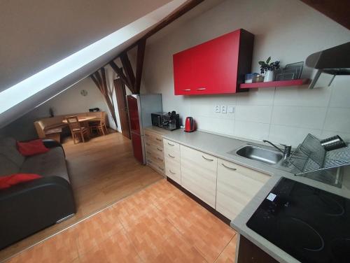 a kitchen with red cabinets and a living room at Lipno -1 Apartmány in Lipno nad Vltavou