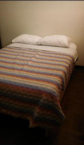 een bed met een gestreepte deken en twee kussens erop bij ManglesChicama in Lima