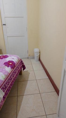 Habitación pequeña con cama y suelo de baldosa. en ManglesChicama, en Lima