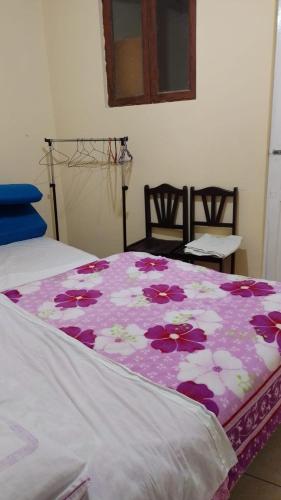 Una cama con una manta rosa y blanca con flores en ManglesChicama, en Lima